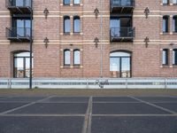 the bicycle is parked in front of a brick building with lots of windows and doors