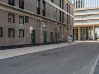 a paved side walk with three bikes parked at the curb and a building in the background