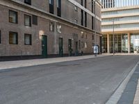 a paved side walk with three bikes parked at the curb and a building in the background