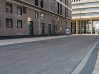 a paved side walk with three bikes parked at the curb and a building in the background