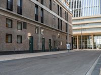 a paved side walk with three bikes parked at the curb and a building in the background