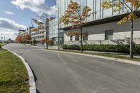 a paved road next to some buildings on a sunny day with trees in the foreground