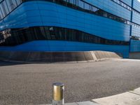 an empty street has a light pole on the side of it and a building with a curved blue exterior