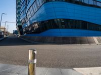 an empty street has a light pole on the side of it and a building with a curved blue exterior