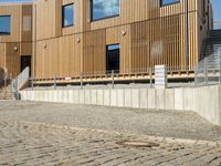 a building that has some steps by it with wooden walls and a bench in front