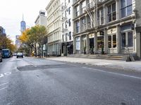 an empty street in a big city with many buildings around it and parked cars on either side