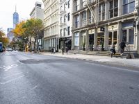 an empty street in a big city with many buildings around it and parked cars on either side