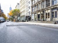 an empty street in a big city with many buildings around it and parked cars on either side