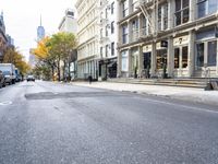 an empty street in a big city with many buildings around it and parked cars on either side