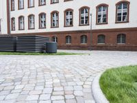 a person skateboarding in the open in a brick courtyard of a building with an overhang