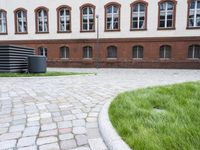 a person skateboarding in the open in a brick courtyard of a building with an overhang