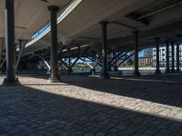 a view of a city from underneath an elevated walkway with benches near it, which has been designed to look like brick