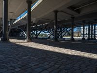 a view of a city from underneath an elevated walkway with benches near it, which has been designed to look like brick