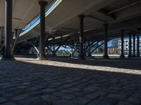 a view of a city from underneath an elevated walkway with benches near it, which has been designed to look like brick