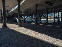 a view of a city from underneath an elevated walkway with benches near it, which has been designed to look like brick