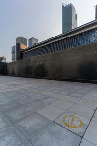 a sidewalk with the letters c painted on it and buildings in the background with a sky line