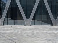 the entrance of a building has many large windows and an outdoor area with people walking