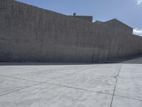 a large cement wall in an empty lot with stairs and buildings around it in the back