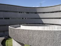 the circular structure is made from concrete bricks, with a lot of grass on the ground below