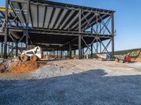 a picture of a building being built on a field near a forest in the background