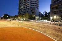 a street that has been lit up with orange lights and street lights on it in the evening