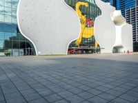 a large white building with three shapes shaped like animals at the base and a large yellow sign in the middle