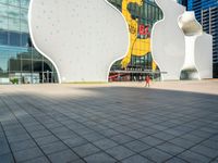 a large white building with three shapes shaped like animals at the base and a large yellow sign in the middle