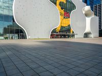 a large white building with three shapes shaped like animals at the base and a large yellow sign in the middle