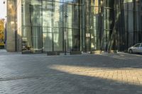 a sidewalk with cars parked on it and tall buildings reflecting in the windows of it