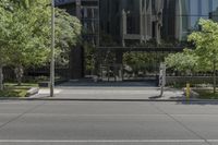 the parking meter is outside of the glass building in the cityscape, near street and trees