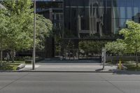 the parking meter is outside of the glass building in the cityscape, near street and trees