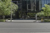 the parking meter is outside of the glass building in the cityscape, near street and trees