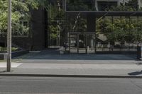 the parking meter is outside of the glass building in the cityscape, near street and trees