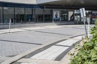 a person sitting at the bench in front of a mall that is empty of people