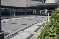 a person sitting at the bench in front of a mall that is empty of people