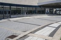 a person sitting at the bench in front of a mall that is empty of people