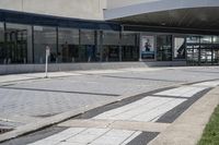 a person sitting at the bench in front of a mall that is empty of people