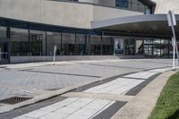 a person sitting at the bench in front of a mall that is empty of people