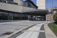 a person sitting at the bench in front of a mall that is empty of people