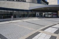 a person sitting at the bench in front of a mall that is empty of people