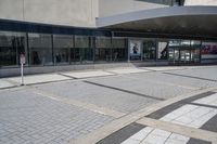 a person sitting at the bench in front of a mall that is empty of people