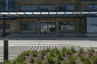 the stairs up to the building next to a sidewalk are made with grass and shrubs