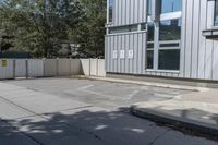 the back side of an apartment building with a fenced off entrance is a white car parked near it