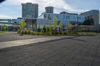 a city street surrounded by grass and tall buildings at the end of a street there is a paved pathway in front of the building