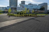 a city street surrounded by grass and tall buildings at the end of a street there is a paved pathway in front of the building