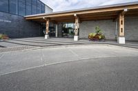 an office building with stone pavers and flower pots in front of it and concrete steps in front