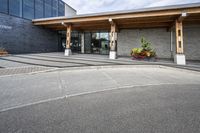 an office building with stone pavers and flower pots in front of it and concrete steps in front