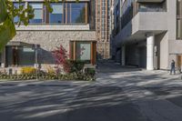 people walk around an empty courtyard surrounded by large buildings on both sides of a street