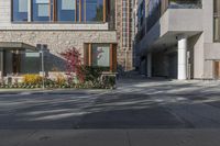 people walk around an empty courtyard surrounded by large buildings on both sides of a street