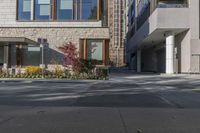 people walk around an empty courtyard surrounded by large buildings on both sides of a street